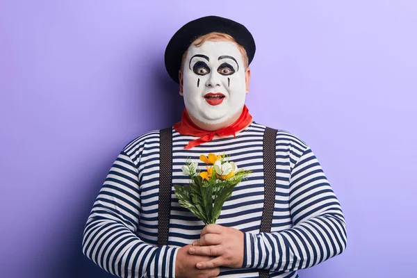 Удивленный эмоциональный клоун с цветами в руках изолированы на белом — стоковое фото