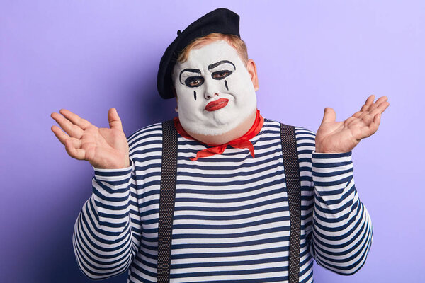 unhappy mime showing shrug gesture isolated on blue