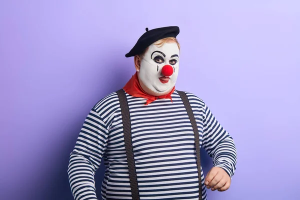 Смешной клоун в черной шляпе, с красным носом на языке — стоковое фото