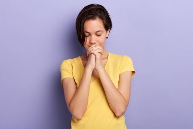 kapalı gözlerle dua eden kadın. Elleri kelepçelerle zincirlenmiş..