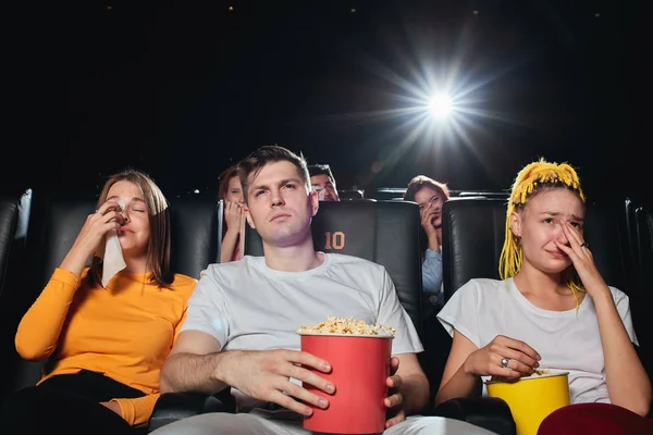 Friends crying while watching sad film at the cinema