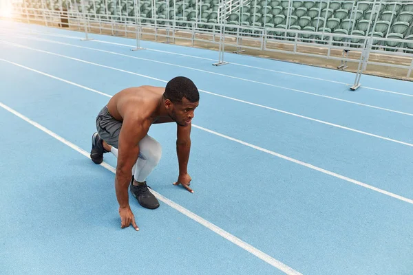 Naked man sitting on the running track and waiting for a whistle — Stock Photo, Image