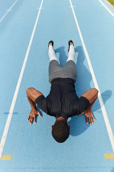 Motivated african athletic young man doing push-ups at the stadium — Stock Photo, Image