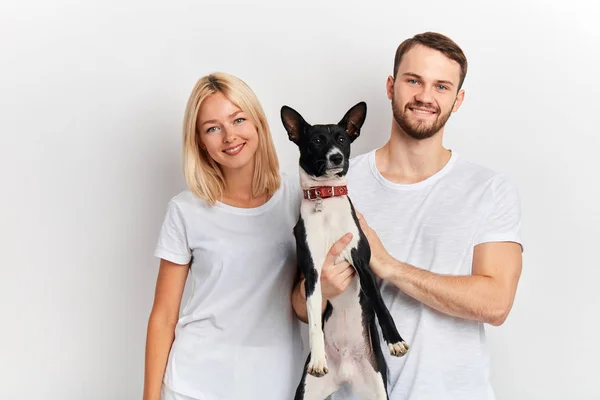 smiling cheerful young man and woman in white T-shirts holding their pet