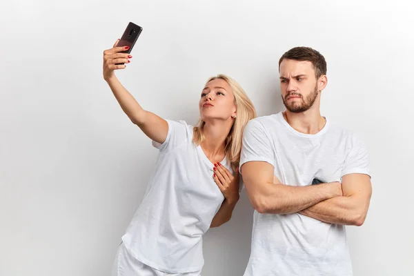 Unhappy man with crossed arms doent want to take selfie with his girlfriend — Stock Photo, Image