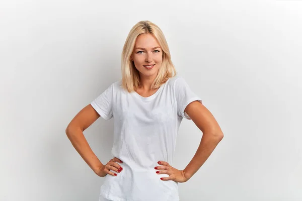 Attraktive Frau im weißen T-Shirt mit den Händen auf den Hüften, die in die Kamera schaut — Stockfoto