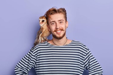 kalçaelleri ile gülümseyen pozitif adam onun kuş ile fotoğraf çekmek için sunuyor
