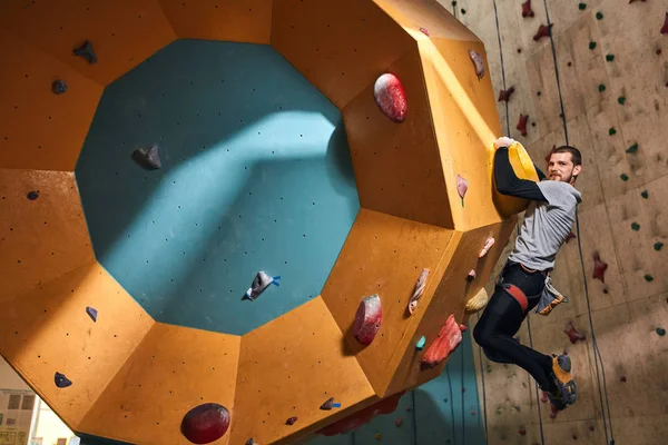 Молодий альпініст з фізичною інвалідністю тренується в приміщенні, висячи на важкій стіні — стокове фото