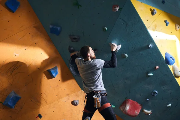 Rock-climber with physical disability hanging on two holds, has strong muscles