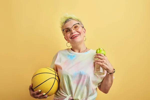 cool old woman working out in the sport center with yellow wall