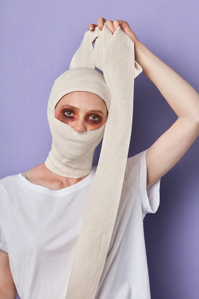 Beaten girl removing a bandage from wound — Stock Photo, Image