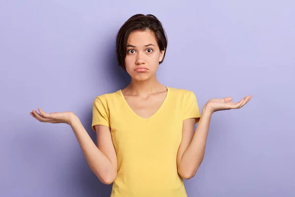 Ernstige verbaasd jonge vrouw haalt schouders, ziet er onzeker en verward — Stockfoto