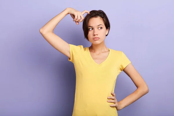 Giovane donna perplessa con mano sul fianco graffiando il dito — Foto Stock