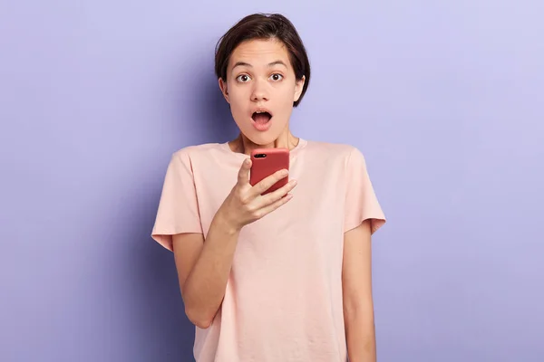 Chica emocional sosteniendo el teléfono inteligente y mirando a la cámara —  Fotos de Stock