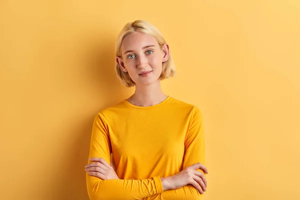 Mujer en suéter amarillo elegante con brazos cruzados mirando a la cámara — Foto de Stock