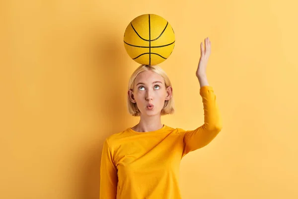 Chica seria mirando la pelota en su cabeza, mujer divirtiéndose con una pelota — Foto de Stock
