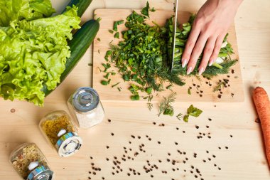 Taze sebzeler, baharatlar ve kadın elleri kesme soğan ile çeşitli şişeler