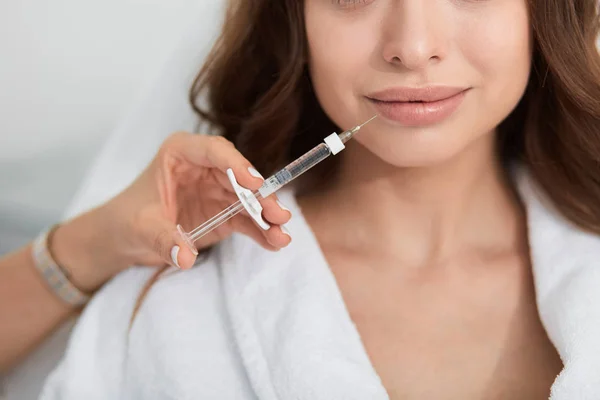 Kozmetikus gazdaság fecskendő közelében női arc, majd ezt injekciót. — Stock Fotó