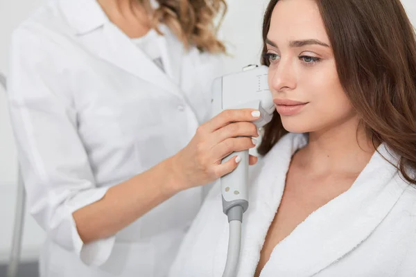 Atrakcyjna brunetka kobieta otrzymująca procedurę podnoszenia RF w centrum urody. — Zdjęcie stockowe