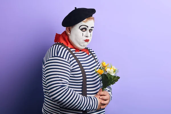 Üzgün depresif pandomim sanatçısı mavi arka plan üzerinde izole çiçek bir buket tutan — Stok fotoğraf