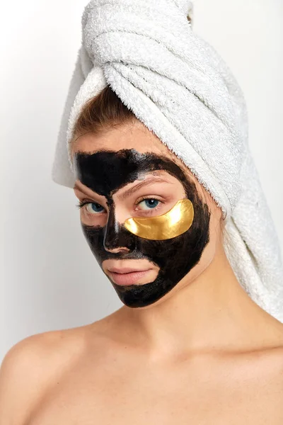 woman with golden under eye patches and black mask posing to the camera