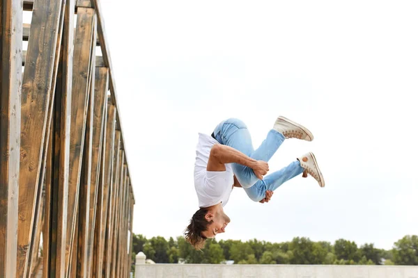 Jovem em roupas casuais elegantes confortáveis fazendo acrobacias loucas — Fotografia de Stock