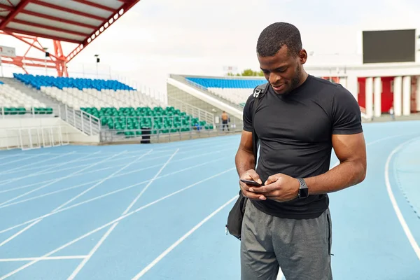 Handsome smiling sportsman using mobile phone — Stock Photo, Image