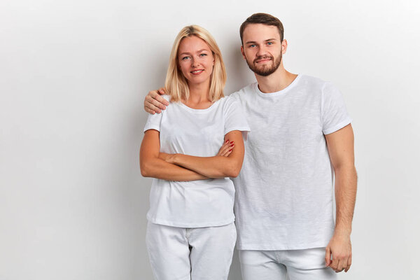 bearded smiling handsome man hugs a woman by the shoulder on a white background