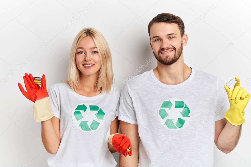 Young cheerul happy couple recycling symbol in their T-shirts sorting batteries,