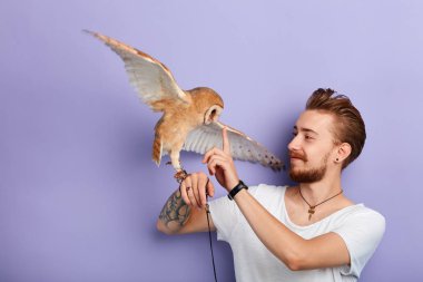 young man teaching an owl to obey the commands, tasks, actions clipart