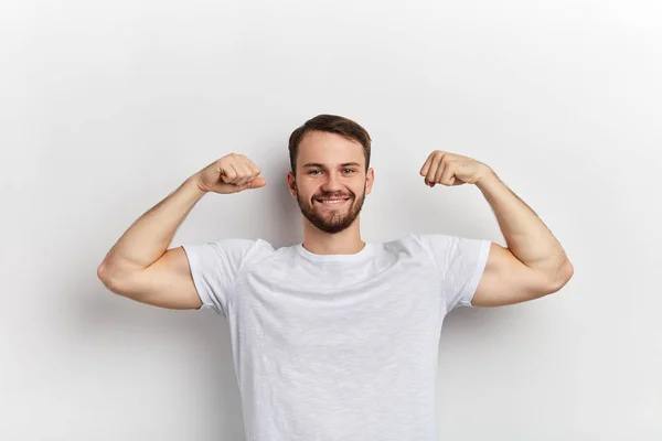 Pozitív ember visel fehér póló, kezében karját fel megmutatni erejét — Stock Fotó