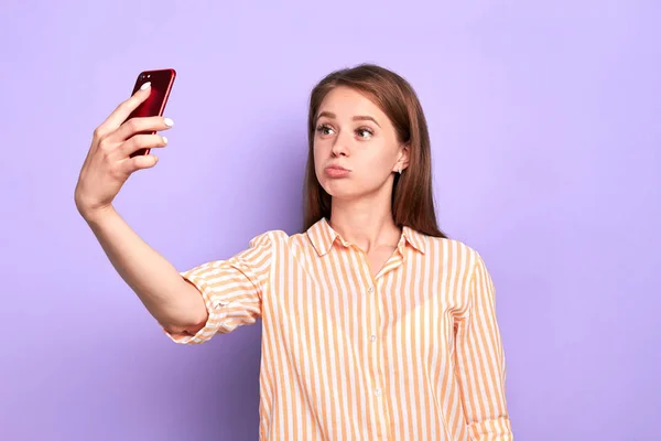 Pretty female student doing selfi photos at her smartphone during break