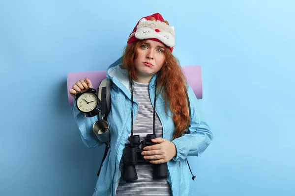 Unglücklich depressive Frau hält Uhr auf isoliertem blauen Hintergrund — Stockfoto