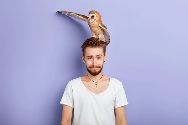 scared man with a bird on his head looking at the camera