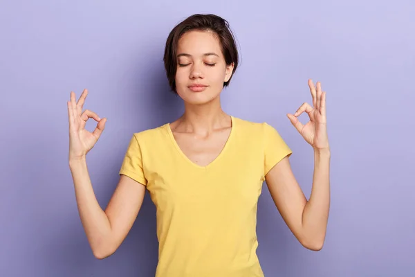 Relaxed careless girl makes mudra sign, relaxes after hard working day — Stock Photo, Image