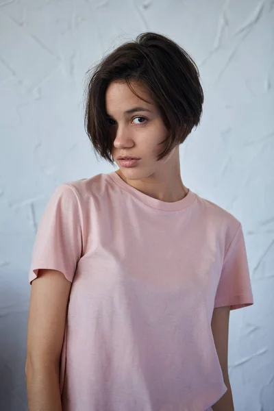 Mladá žena ve stylovém růžovém tričku pro kameru — Stock fotografie