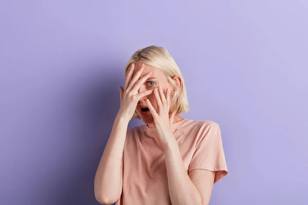 Jonge bang vrouw bedekt haar gezicht met handen en spionnen — Stockfoto