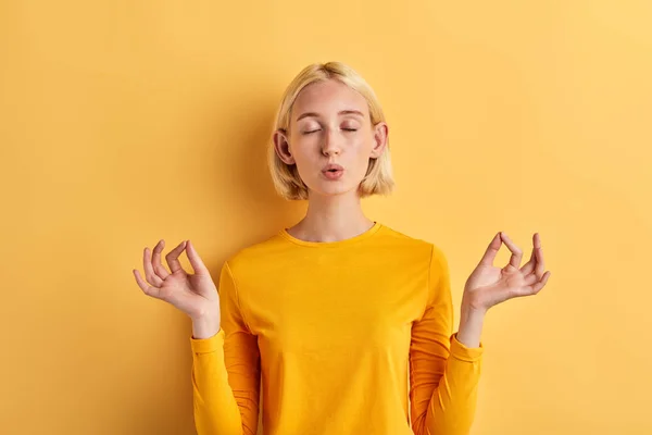 Привлекательная девушка в стильном желтом джампере занимающаяся йогой, медитацией — стоковое фото