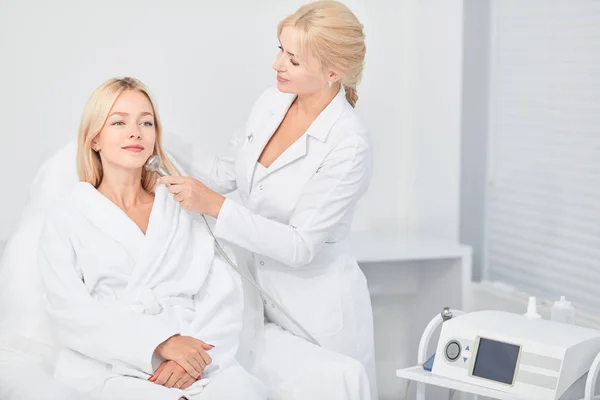 Lady in sitting and professional cosmetologist cleaning with dermabrasion tool — Stock Photo, Image