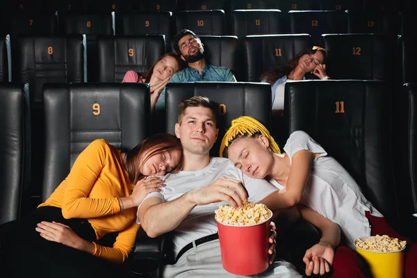 young people sleeping during boring movie in cinema