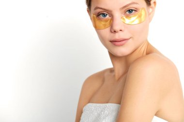 gözlerinin altında sarı maskeli genç kadın kameraya bakıyor.