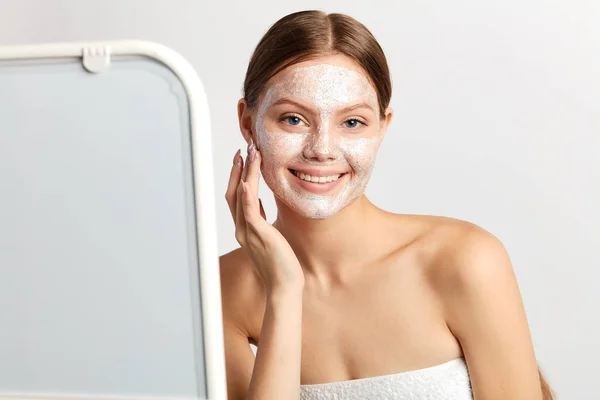Glad ung kvinna stående framför spegeln med mask på hennes ansikte. — Stockfoto