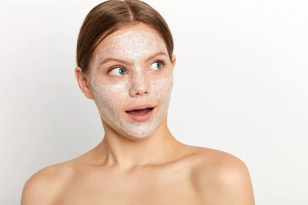 Wanita muda dengan masker wajah putih mengurus kecantikannya — Stok Foto