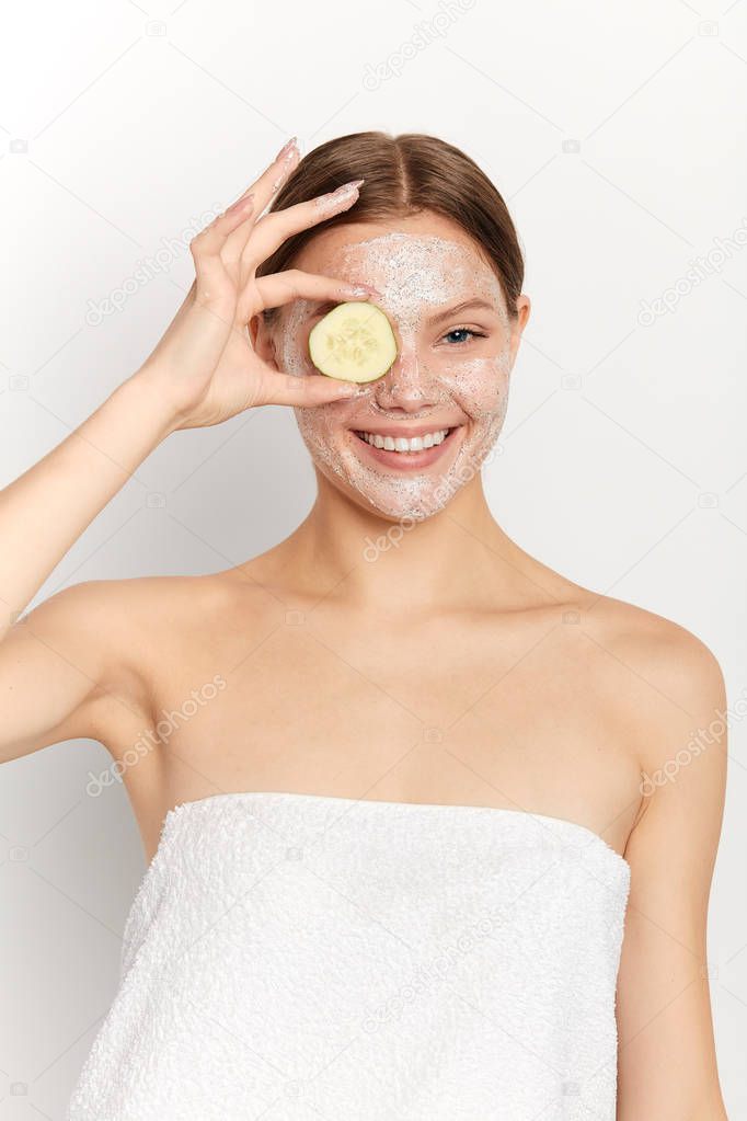 cheerful attractive girl having fun with a cucumber at spa salon