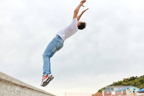 Young man doing back flip in the street. Sport Activities outdoors.