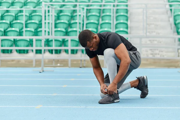 African guy tying shoelaces at the stadium — Stock Photo, Image