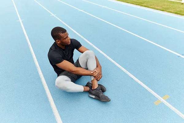 Mixed race serious sportsman sitting on running track at stadium, — Stock Photo, Image