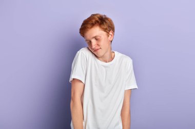 Genç utangaç ve belirsiz adam ellerini cebinde tutar, kenara bakar