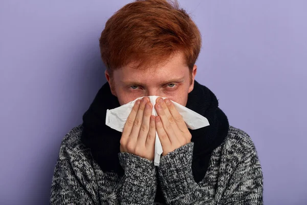Joven infeliz hombre serio cubre su nariz parte de la cara por toalla de papel —  Fotos de Stock