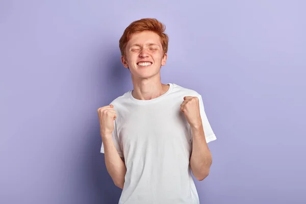 Cheerful smiling man with closed eyes clenches fists celebrates success — Stock Photo, Image